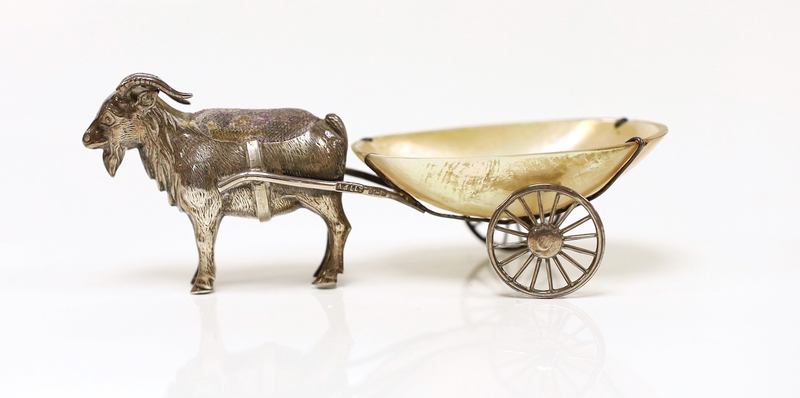 A George V silver and mother of pearl mounted novelty pin cushion, modelled as a goat pulling a cart, Adie & Lovekin, Birmingham, 1911, 11.2cm.